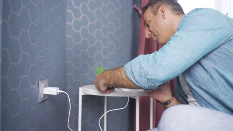 hombre conectando el cargador de teléfono móvil a la toma de corriente de la pared.