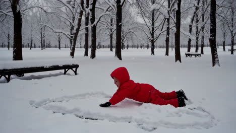 child in red snowsuit playing in a snowy park