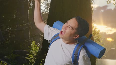 vista lateral de cerca de un excursionista masculino asiático con mochila de montañismo gritando meta celebrando el éxito mientras explora la naturaleza del bosque