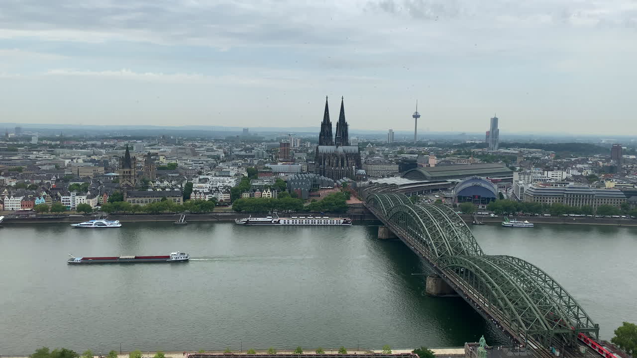 Aerial wide shot of cologne city with famous bridge, ship on rhine river and cityscape with church in background