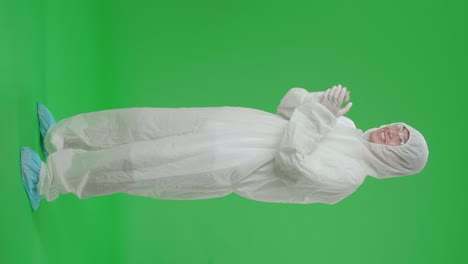 side view of full body asian man wearing personal protective equipment uniform ppe and clapping his hands in the green screen studio