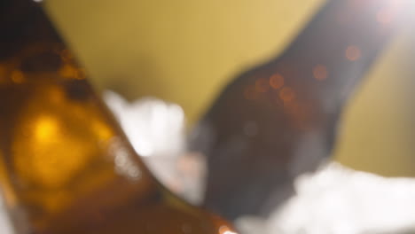 primer plano de una persona que toma una botella de vidrio refrigerada de cerveza fría o bebidas gaseosas de un cubo lleno de hielo contra un fondo amarillo 3