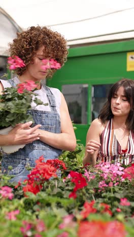 garden center employee showing flowers to customer. vertical