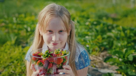 a baby holds a bowl of strawberries