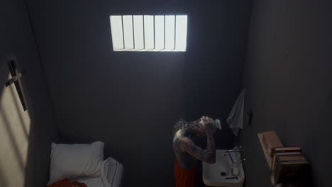 high angle view of tattooed man applying shaving foam to his head in prison