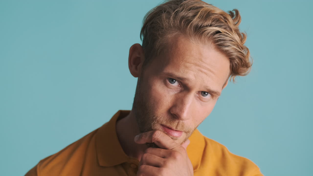 파란색 배경 위에 포즈를 취하는 매력적인 수염이 있는 남자