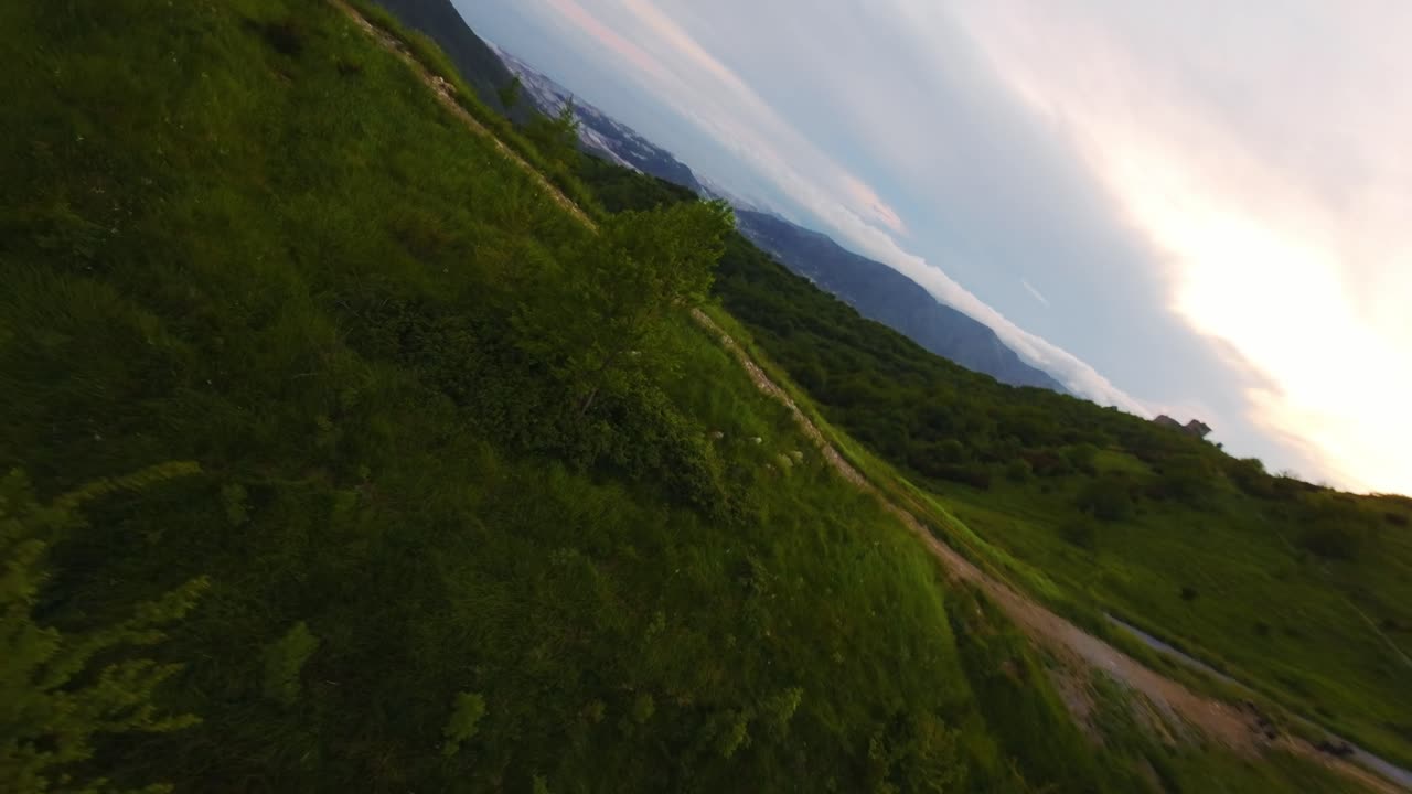 Green hills and winding paths captured by an fpv drone in nature, aerial view