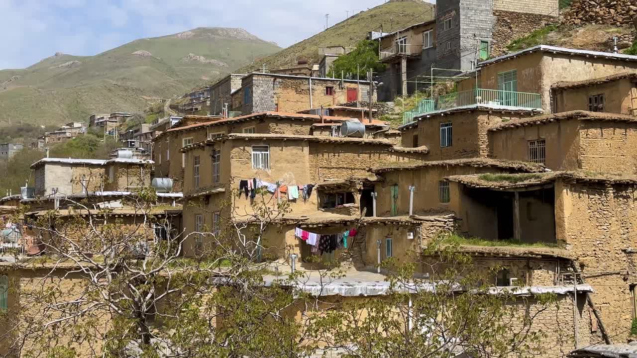 Stupňovitá terasovitá vesnice v kurdských horách Zagros s původní kurdskou architekturou z hliněných cihel (adobe), tradiční venkovská osada využívající udržitelnou hlínu. Turecký venkov, autentická kulturní krajina.