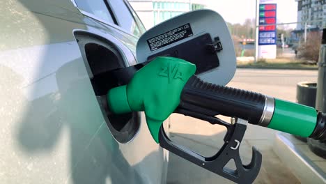 automobile is getting refueled by a petrol pistol