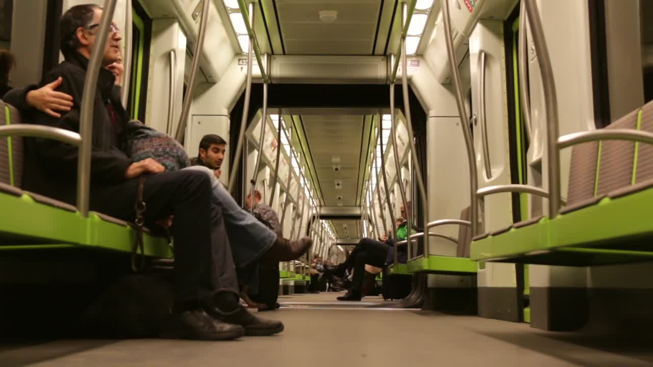 People using public transportation via subway in europe, sitting down enjoying ride and talking to each other in conversation