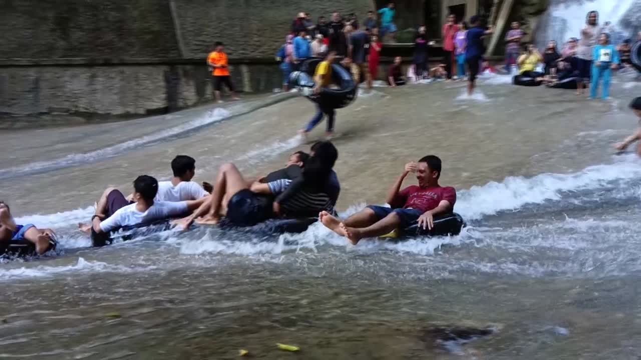 Tourist playing water with tires in front of the Bantimurung waterfall in Maros, South Sulawesi. Karst park.