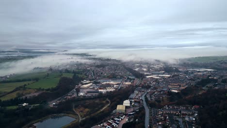 Aerial-footage-of-a-mist-covered-urban-district-town-in-Yorkshire-UK,-showing-busy-roads-traffic-and-red-brick-houses