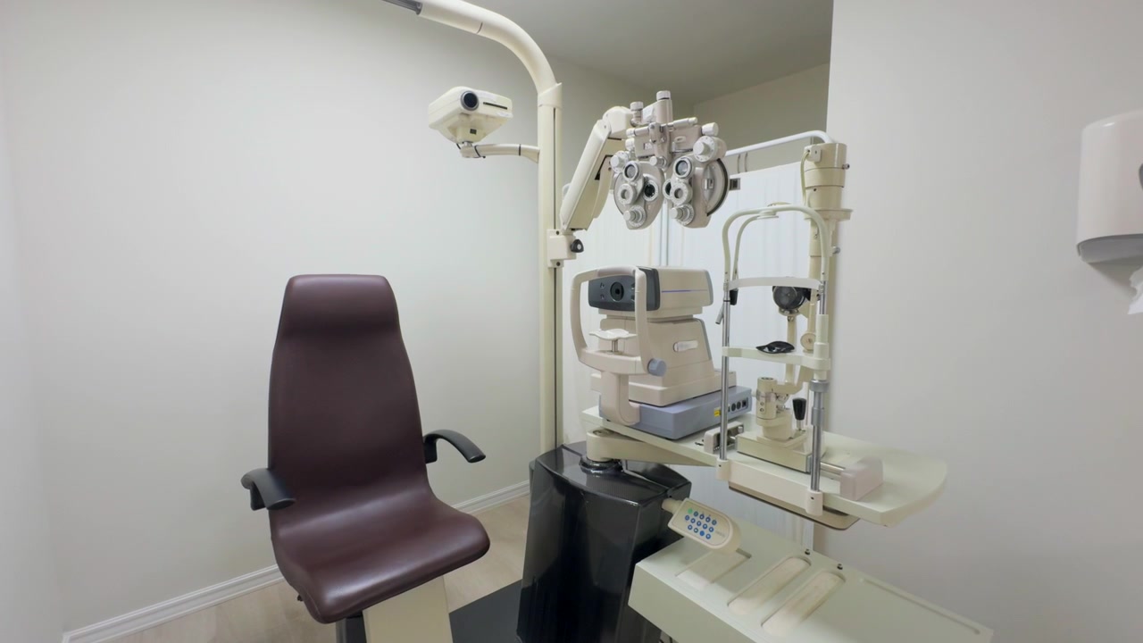 A modern optometry examination room featuring an ophthalmic chair, a phoropter, and other eye diagnostic equipment in a clean and professional setting.