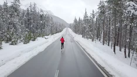 Aerial-view-of-a-man-running-on-a-road-in-a-snowy-forest-in-Switzerland