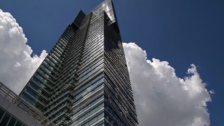 Vista em ângulo baixo de um arranha-céu moderno contra um céu nublado, capturando as linhas elegantes do edifício.