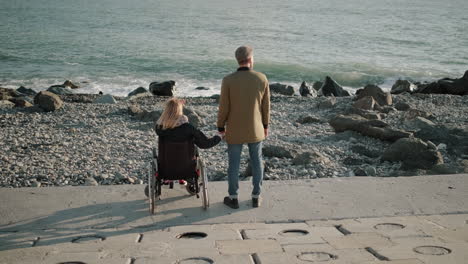 pareja en la playa, con una persona en silla de ruedas.