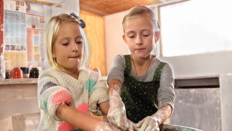 Girl-assisting-her-sister-while-making-a-pot