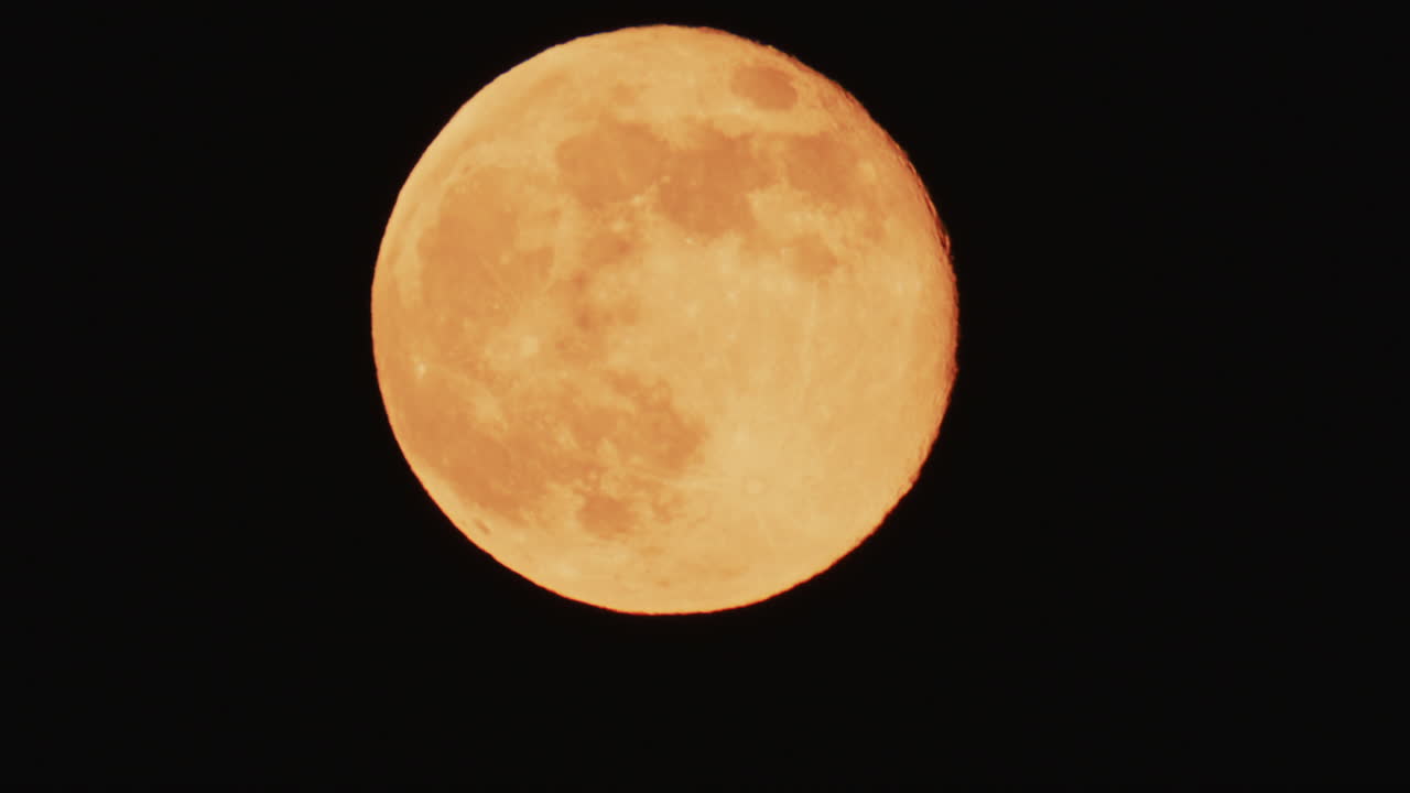 Large full moon rising against a dark night sky with clear details and dramatic atmosphere