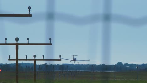 pequeño avión de entrenamiento blanco con motores de hélice aterrizando en el aeropuerto en un día soleado de verano, plano medio desde la distancia