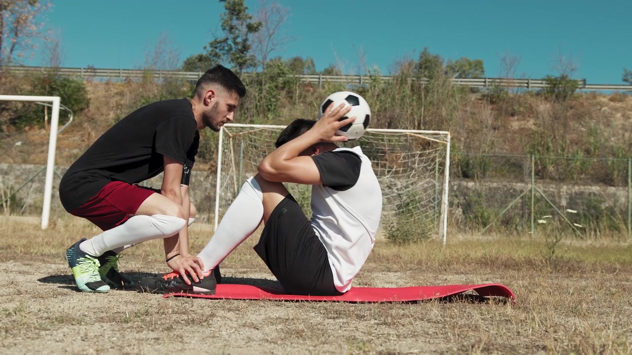 Two Players Helping Each Other During Abs Training