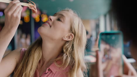 hermosa mujer rubia comiendo mariscos en un restaurante con una amiga usando un teléfono inteligente tomando fotos amigos chicas divirtiéndose compartiendo el fin de semana juntos en las redes sociales 4k