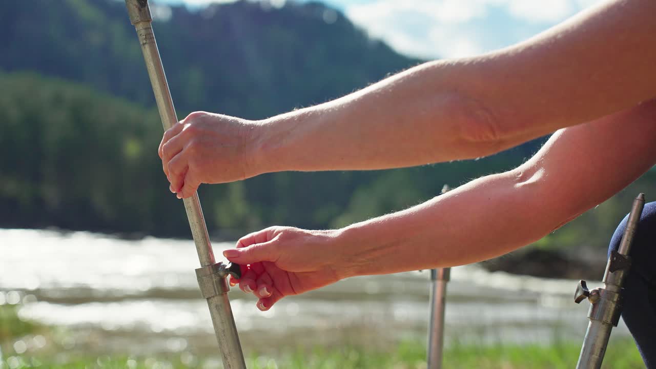 Primo piano di mani che regolano un supporto metallico all'aperto lungo un fiume.
