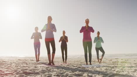 Mujeres-Atléticas-Realizando-Yoga-En-La-Playa