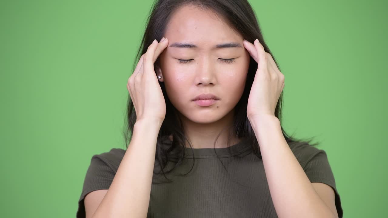 Young stressed Asian woman having headache