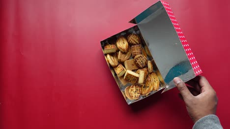 a person's hands reaching into a box of cookies