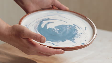 hands holding a ceramic plate