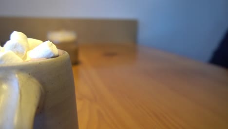 3-3-Bokeh-Hintergrund-Im-Café-Mit-Verschwommenen-Kunden,-Die-Am-Tisch-Sitzen-Und-Heiße-Schokolade-Mit-Marshmellows-Eisglas-Aus-Mokka-Auf-Holztisch-Genießen,-Tagsüber-Rotierende-Nahaufnahme-Tischansicht