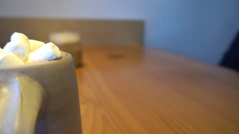 3-3 bokeh de fondo en la cafetería con clientes borrosos sentados en una mesa disfrutando de chocolate caliente con marshmellows, tarro de cristal helado de moka en una mesa de madera durante el día, vista giratoria de la mesa cerrada