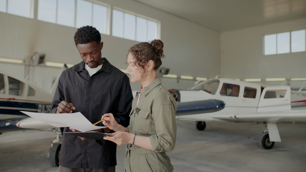 Two Technicians Discussing Aircraft Documents Inside Hangar