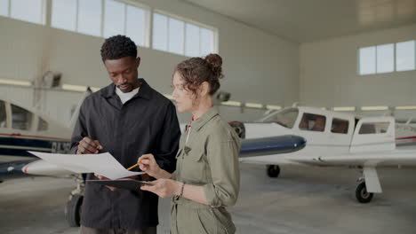 two technicians discussing aircraft documents inside hangar