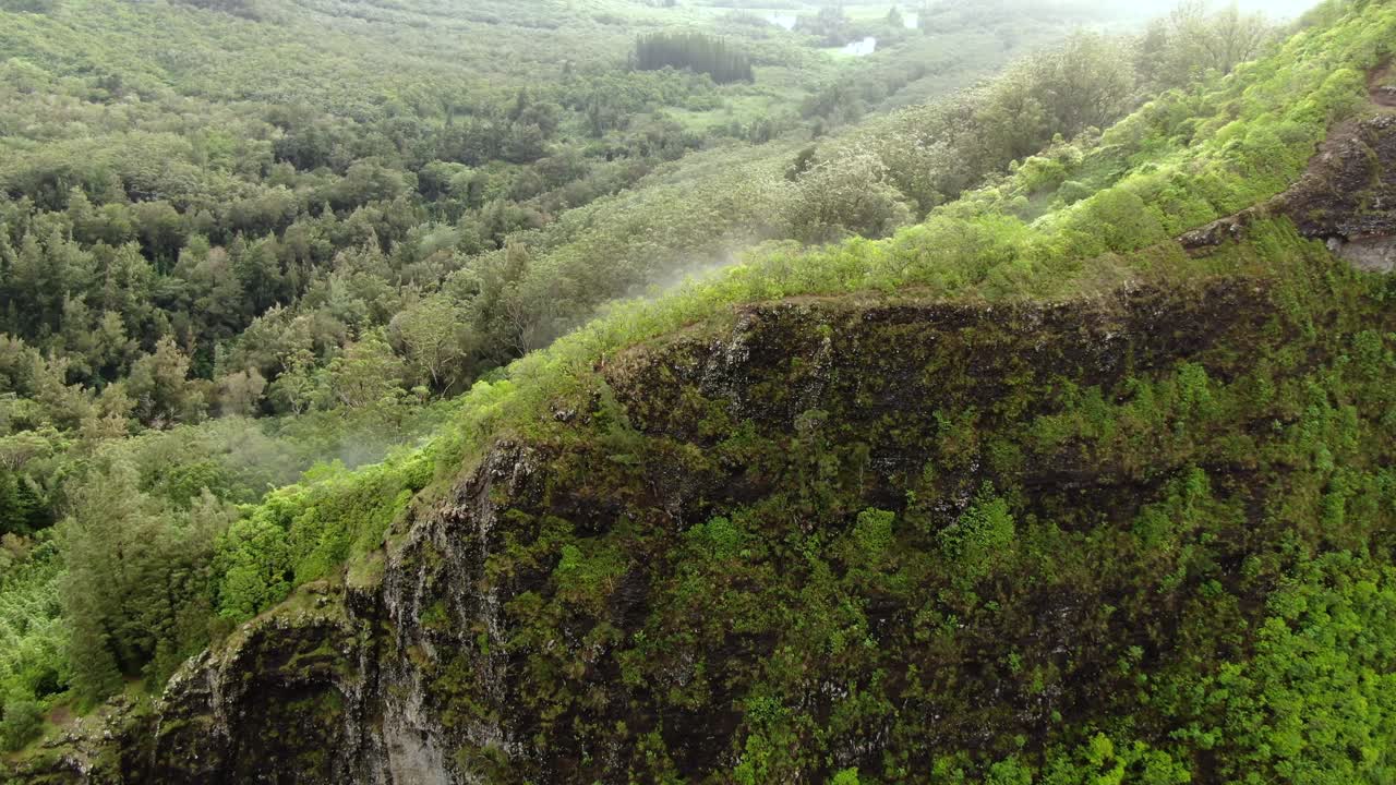 drone volando sobre los excursionistas en la cresta de la montaña del este de oahu en un día lluvioso mientras la niebla flota sobre la selva tropical