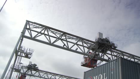 Logistics-international-cargo-harbour,-container-crane-moves-goods,-dutch-angle