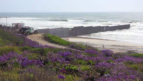 een voertuig van de grenspatrouille kijkt toe terwijl de golven het strand oprollen bij het grenshek van de vs mexico in de stille oceaan tussen san diego en tijuana