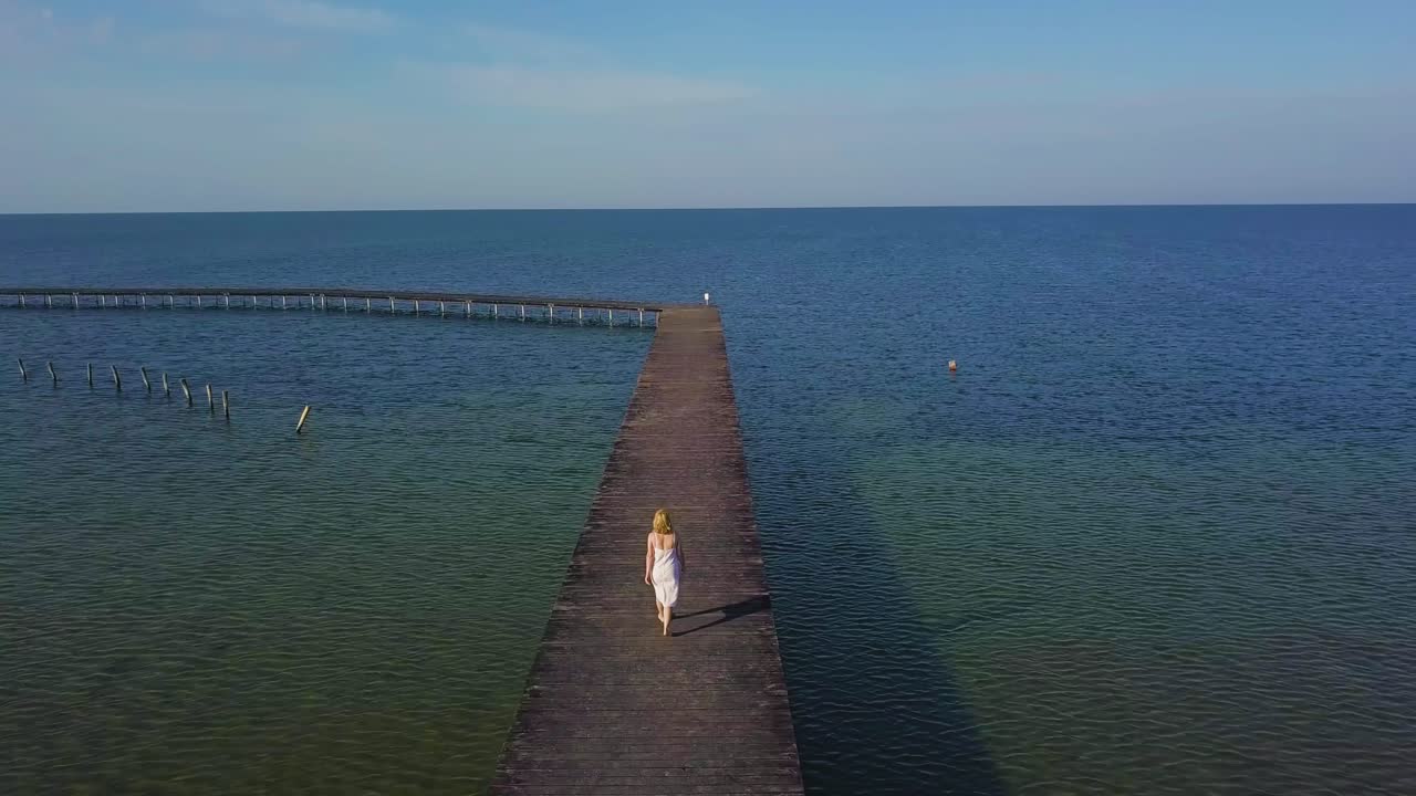 A girl walks on a wooden pier near the sea 03