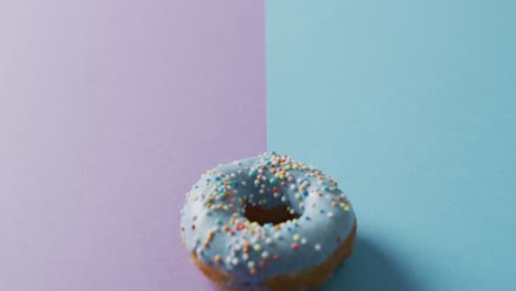 Video-Von-Donut-Mit-Zuckerguss-Auf-Violettem-Und-Blauem-Hintergrund