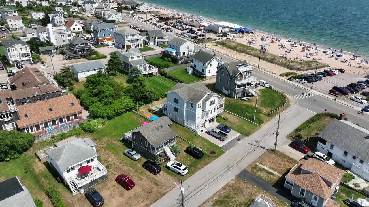 Enfamiliehuse i strandstil nær sandstranden Misquamicut, Rhode Island. Luftoptagelse fra oven. Blåt havlandskab og afslappende mennesker ved kysten. Vidvinkeloptagelse. Luksushjem i forstad.