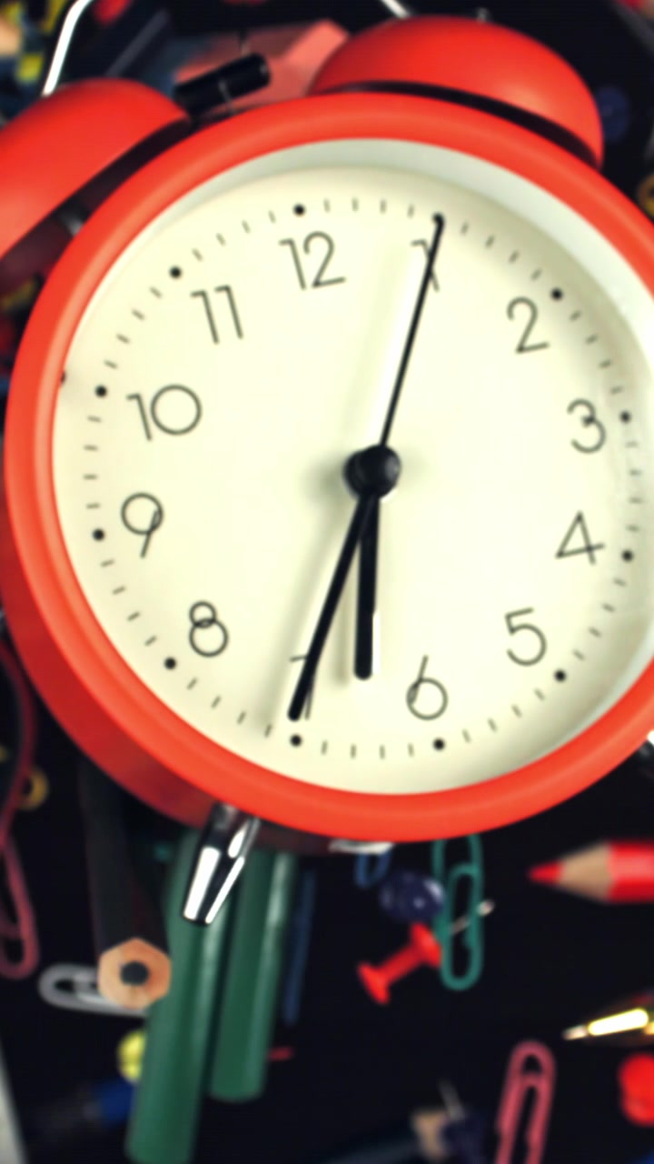 Red Alarm Clock Ticking Amidst Colorful Stationery Items