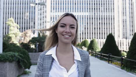 young businesswoman walking in financial district while looking at camera