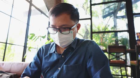 수술 마스크를 착용한 젊은 사업가가 인터넷에 연결된 스마트 폰을 통해 고객들과 비디오 컨퍼런스를 하고 있습니다.