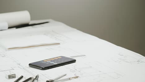 professional hands working on blueprints with a smartphone calculator