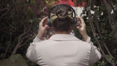 girl placing headphones on her head in nature