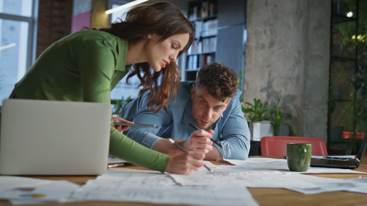 Focused architects collaborating workplace looking documents work papers closeup