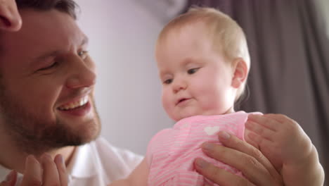 adorable niña en el abrazo del padre. retrato de un bebé jugando con mamá y papá