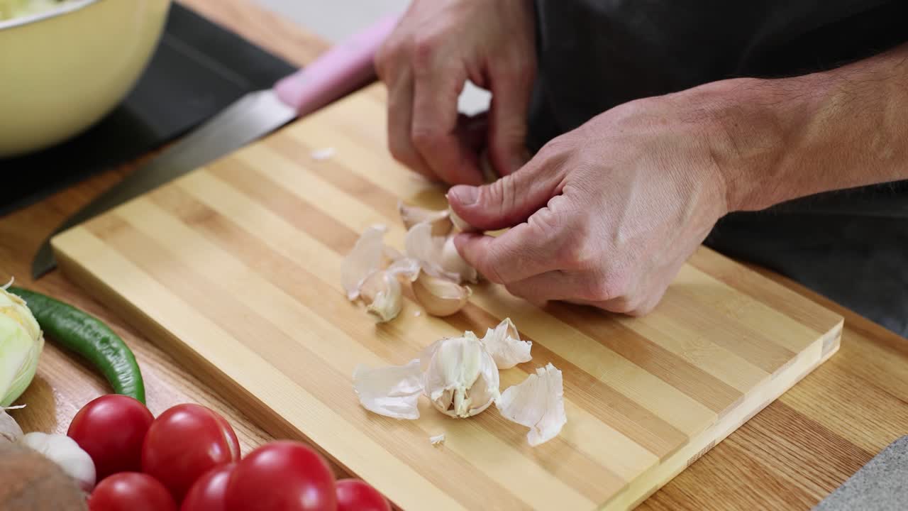 Close-up of hands peeling garlic on a wooden cutting board