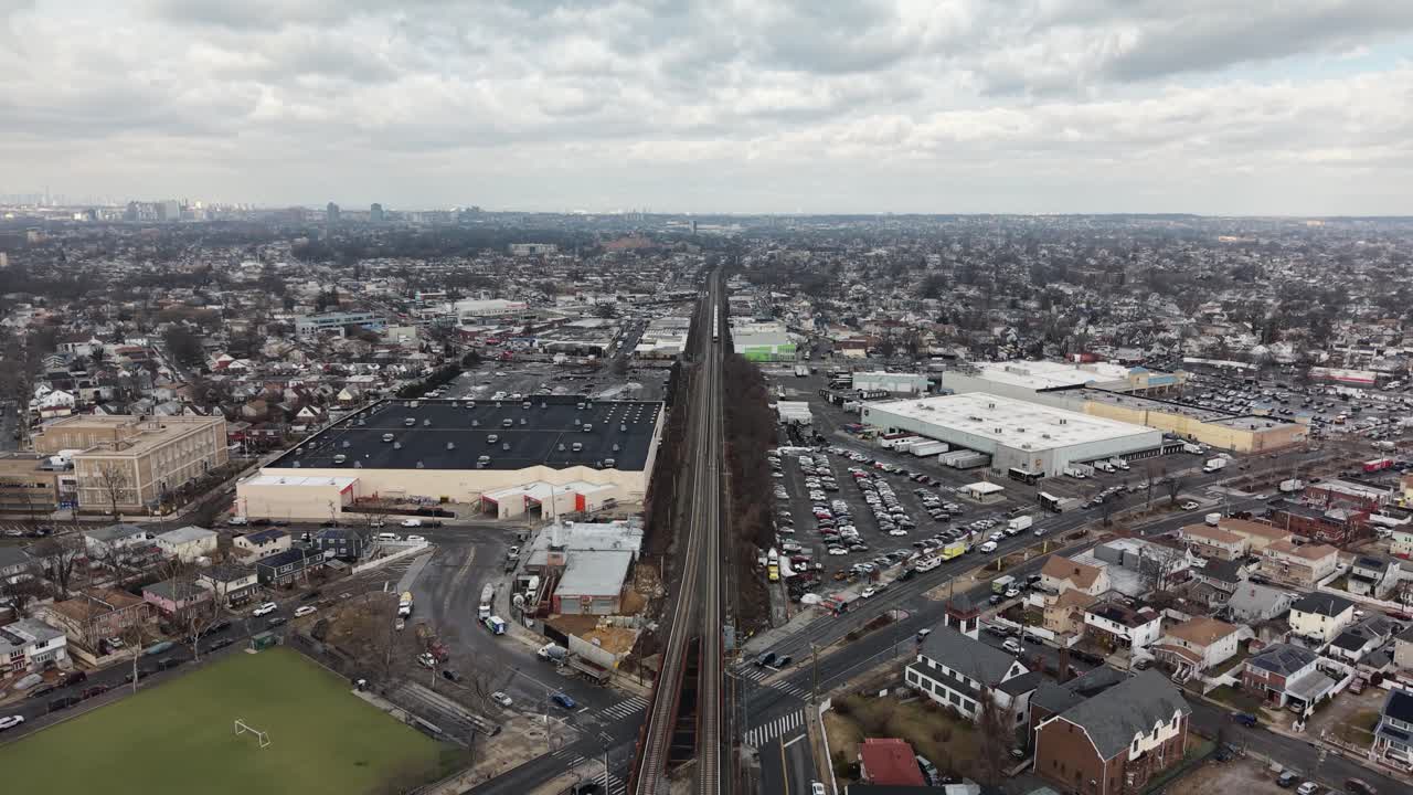 Dronebilde av Queens, New York, fra luften langs jernbanen som skjærer gjennom en tettbygd forstad i New Jersey med hus, gater og overskyet himmel