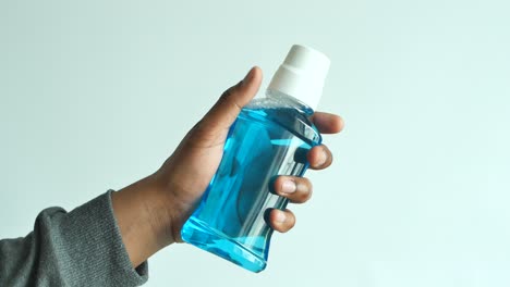 hand holding a blue mouthwash bottle